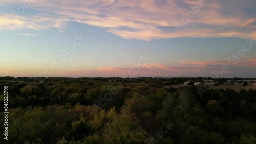 Drone flying over the wooded area at sunset with a cloudy sky in the background, Fate, Texas, US