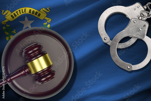 Nevada US state flag with judge mallet and handcuffs in dark room. Concept of criminal and punishment