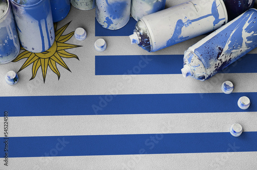 Uruguay flag and few used aerosol spray cans for graffiti painting. Street art culture concept photo