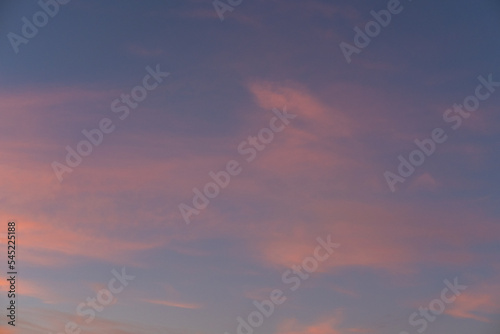 Moody sunset or sunrise sky with rays of light illuminating dark blue and bright and soft pink and orange clouds. © Alena