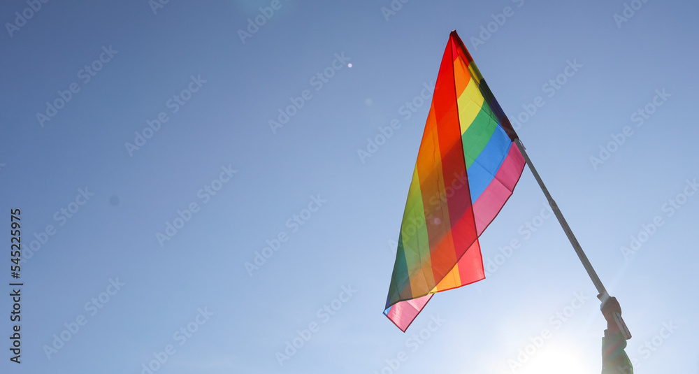 Look up view of rainbow LGBT flag waving in the blue sky background, soft and selective focus, copy space. To celebrate LGBT communities in pride month Look up view of rainbow LGBT flag waving in the blue sky background, soft and selective focus, copy space. To celebrate LGBT communities in pride month