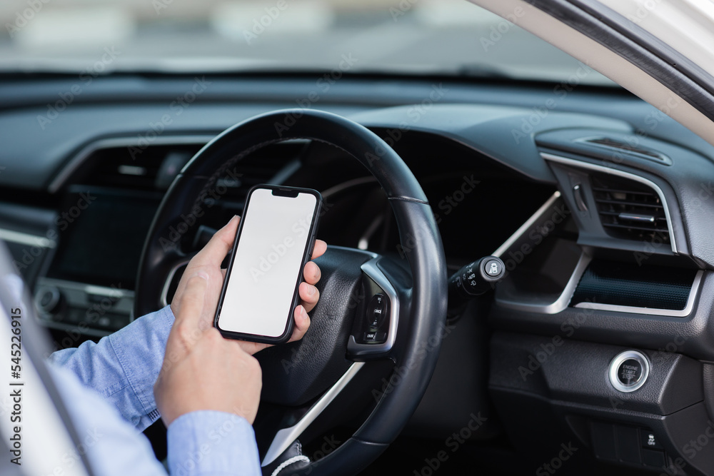 Close-up shot of the driver using a smartphone with a blank white screen inside the car. Man looking at location, finds smartphone screen through gps navigator application.