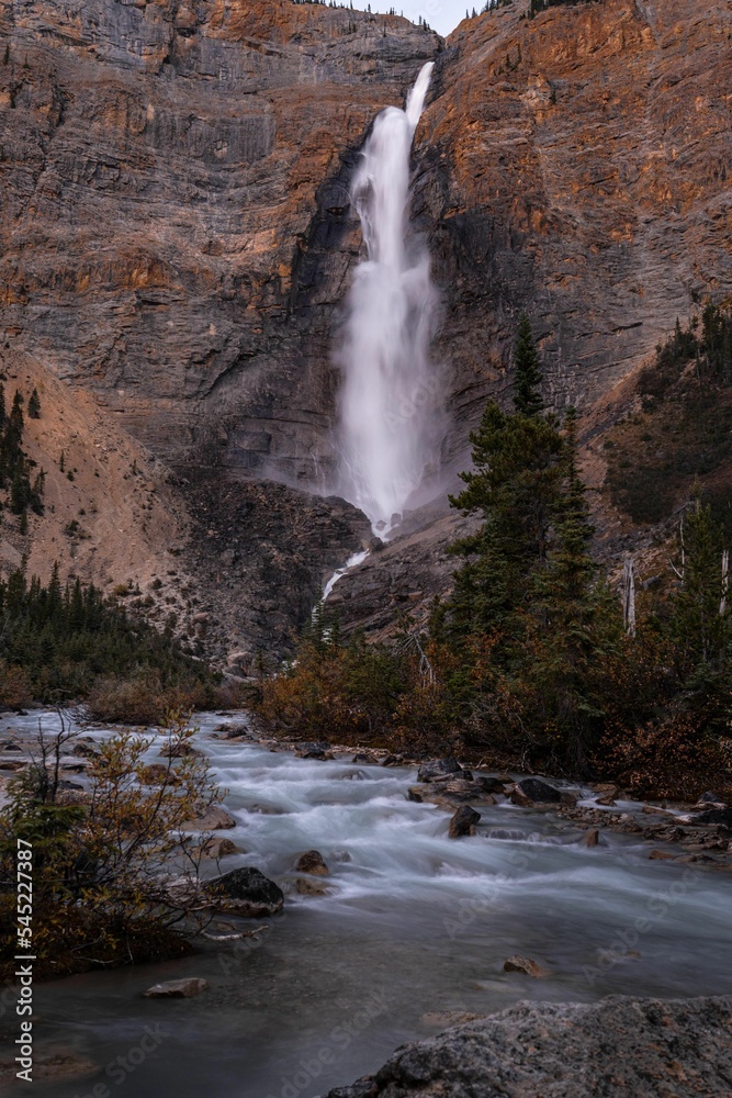 Vertical shot of a waterfall flowing down between cliffs Vertical shot of a waterfall flowing down between cliffs