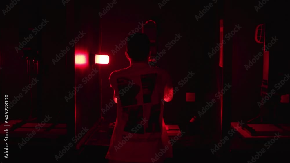 Caucasian young man developing analog photography in a dark room.