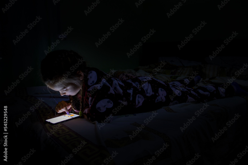 Obraz premium A girl with a mobile phone on the bed.