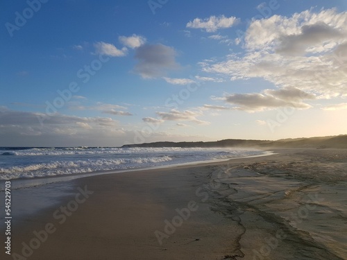 Landscape of a sandy beach under blue cloudy sky at sunrise © Patrick Helm/Wirestock Creators