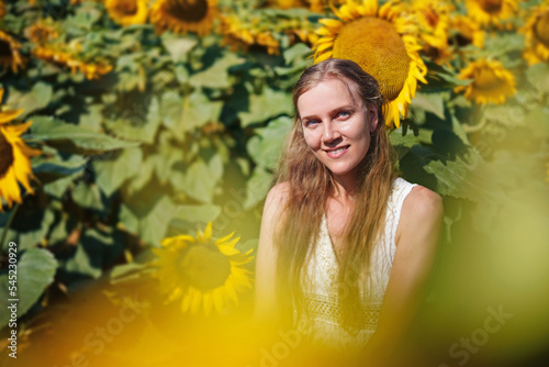 Young beautiful woman stands in the middle of field of sunflowers, freedom, resilience, courage. Art Theme Ukraine. Postcard to support war refugees. Sunflowers are a symbol of hope. Stay with Ukraine