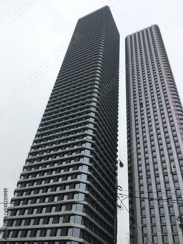 Twin modern looking highrise apartment buildings on grey sky in Moscow