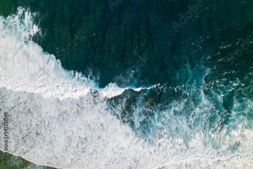 Aerial view of the ocean waves with white foam on a sunny day. Great for wallpaper