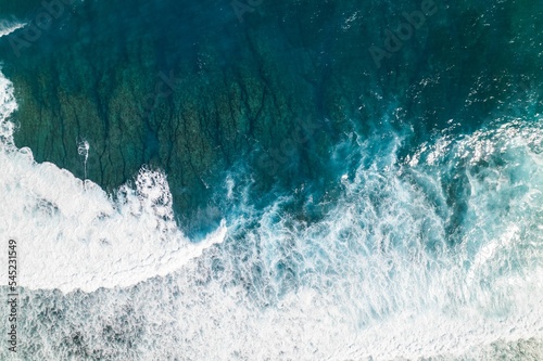 Aerial view of the ocean waves with white foam on a sunny day. Great for wallpaper