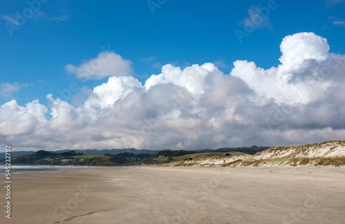 Sandy beach against blue sea in Waipu Cove, the Northland region, New Zealand under a cloudy sky