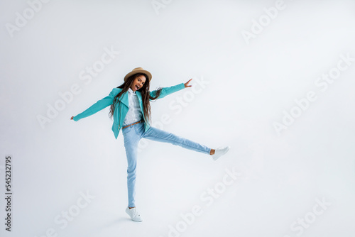 Full length photo of a charming young black woman in casual clothes jumping on a light background. 