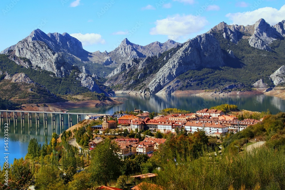 Awesome shot of a small village by the river, mountains in background in Riano reservoir Leon Spain