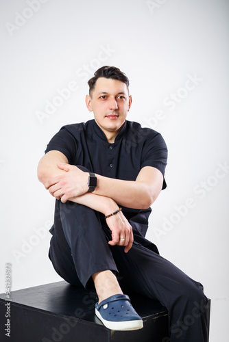 An adult man of European appearance wearing a black medical suit