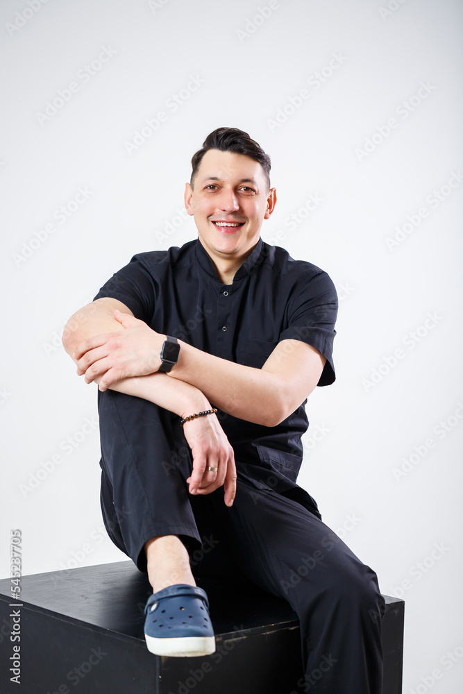 An adult man of European appearance wearing a black medical suit An adult man of European appearance wearing a black medical suit