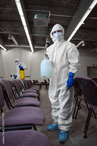 Cleaner wearing personal protective gear during disinfection of furniture