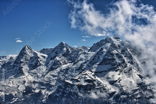 Snowy peaks of mountain range under a blue cloudy sky