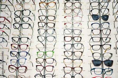  lot of glasses on display in optical store. Many eyeglasses and sunglasses for sale.