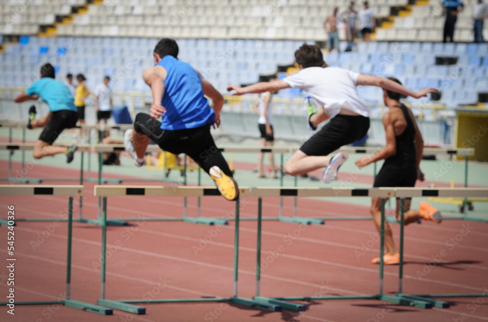 Runners races over hurdles is a sport competition. Athletes hurdling sport in athletics in a stadium