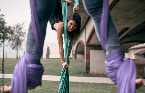 Young caucasian woman teaching her friends how to do some aerial silks exercises and amazing positions. © FranciscoJavier