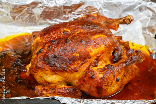 Whole baked chicken carcass stuffed with pears in soy sauce with a crispy crust on foil.