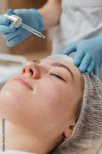Beautician applies cleanser and moisturizer to the face with a dropper