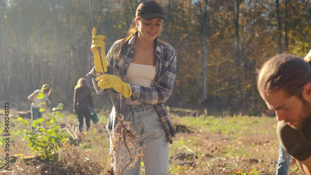 Young happy Caucasian woman bringing seedling of tree and man digging ...
