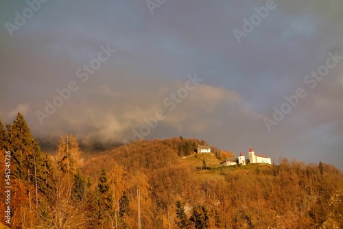 Landscape shot of the Church of St. Primoz and Felicijan on top of the golden hill in fall