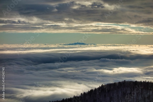 Breathtaking scenery of fluffy white clouds from a hilltop during golden hour © Jani Sušnik/Wirestock Creators