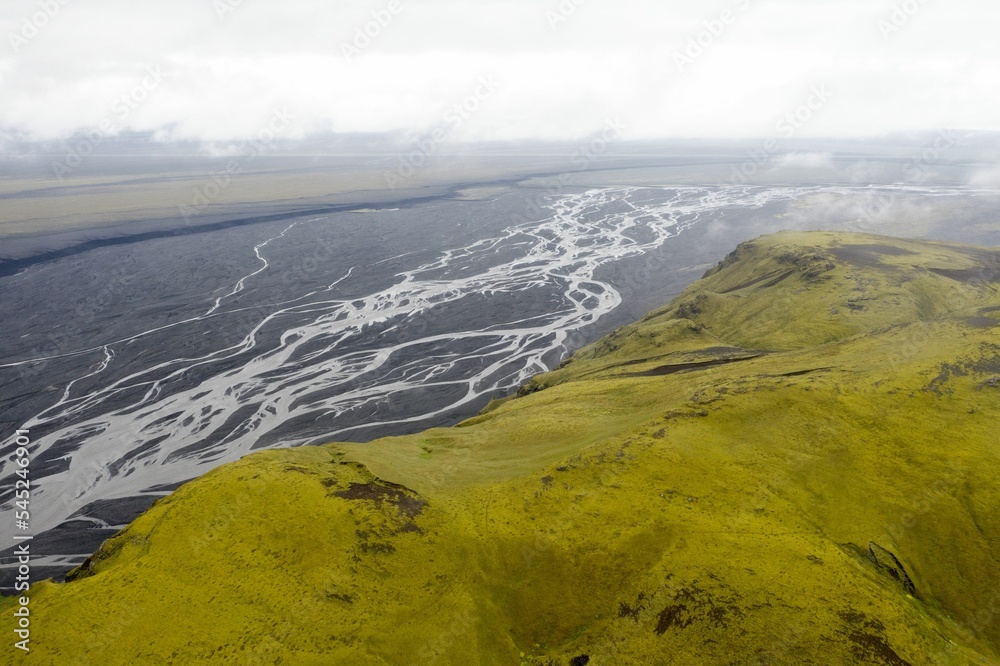 Aerial shot of a river flowing trough the green-covered mounts in the Katla Geopark, Iceland Aerial shot of a river flowing trough the green-covered mounts in the Katla Geopark, Iceland