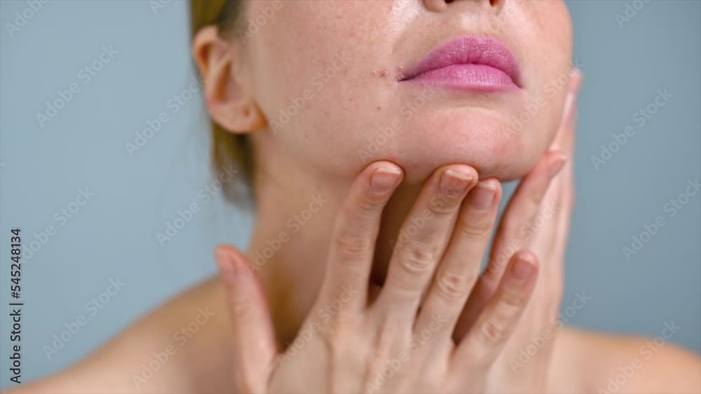 A young caucasian woman is moisturizing face and skin with cosmetic oil while doing a facial massage. Slow motion A young caucasian woman is moisturizing face and skin with cosmetic oil while doing a facial massage. Slow motion