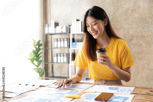 Young asian designer woman drawing a website outline and website ux app development on mobile phone.