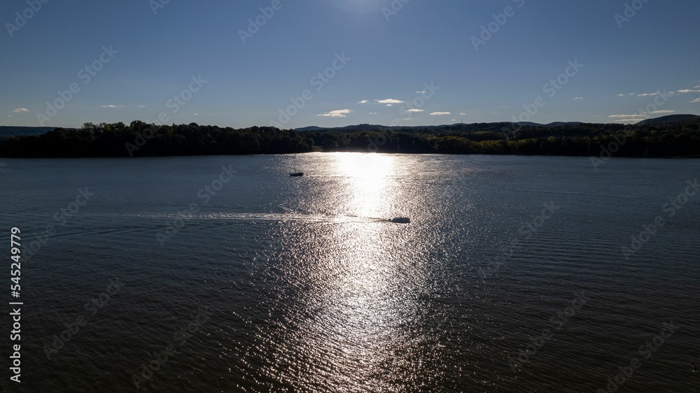 Sunlight reflected in Hudson River in the evening with few boats under blue sky