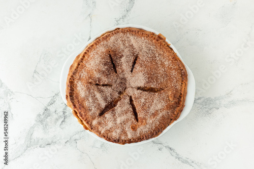 Homemade apple pie on the white marble background with cinnamon flavor covered with sugar Flaky Crust. Traditional autumn dessert for Thanksgiving Day. Flat lay