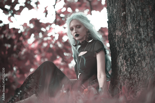 Fototapete Dark goth girl standing in the forest, portrait of a wiccan witch performing mag