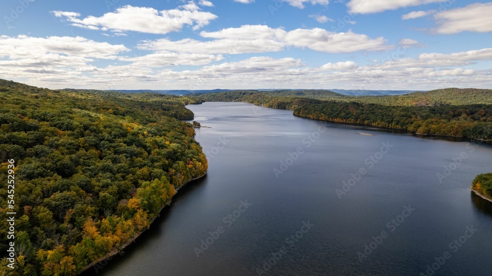 Drone shot of the New Croton Reservoir on a sunny day in autumn with a blue cloudy sky