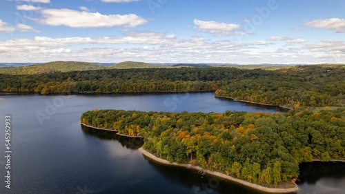 Drone shot of the New Croton Reservoir on a sunny day in autumn with a blue cloudy sky