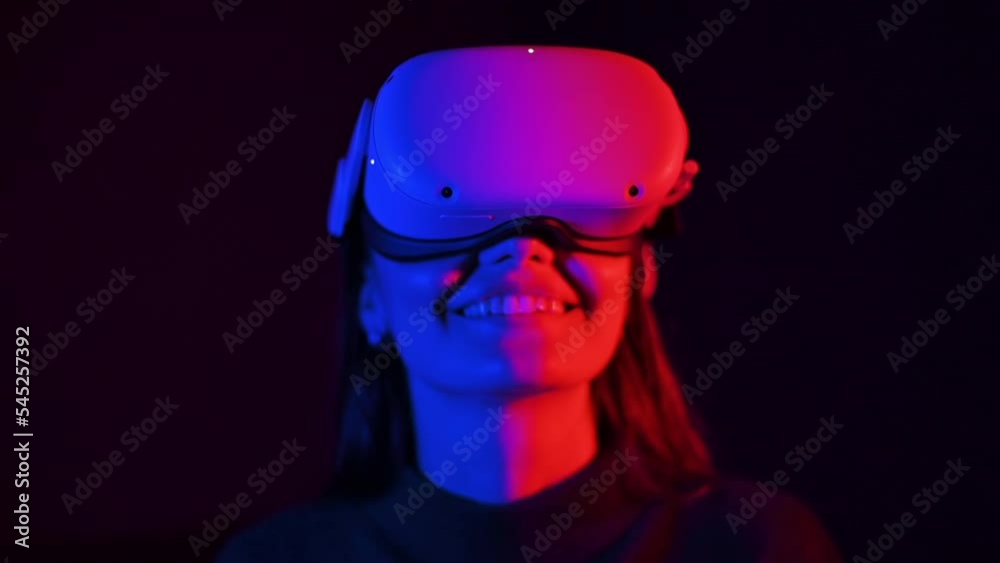 A young woman is excited while wearing VR glasses, Red and blue illumination. Slow motion A young woman is excited while wearing VR glasses, Red and blue illumination. Slow motion