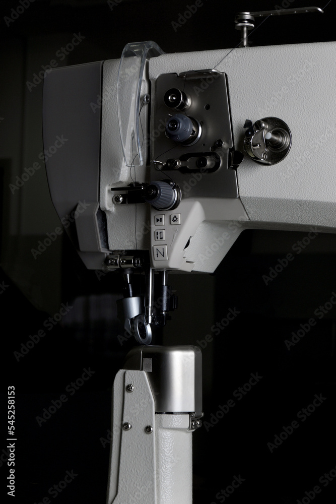 industrial sewing machine with a needle in work on black background. industrial sewing machine with a needle in work on black background.