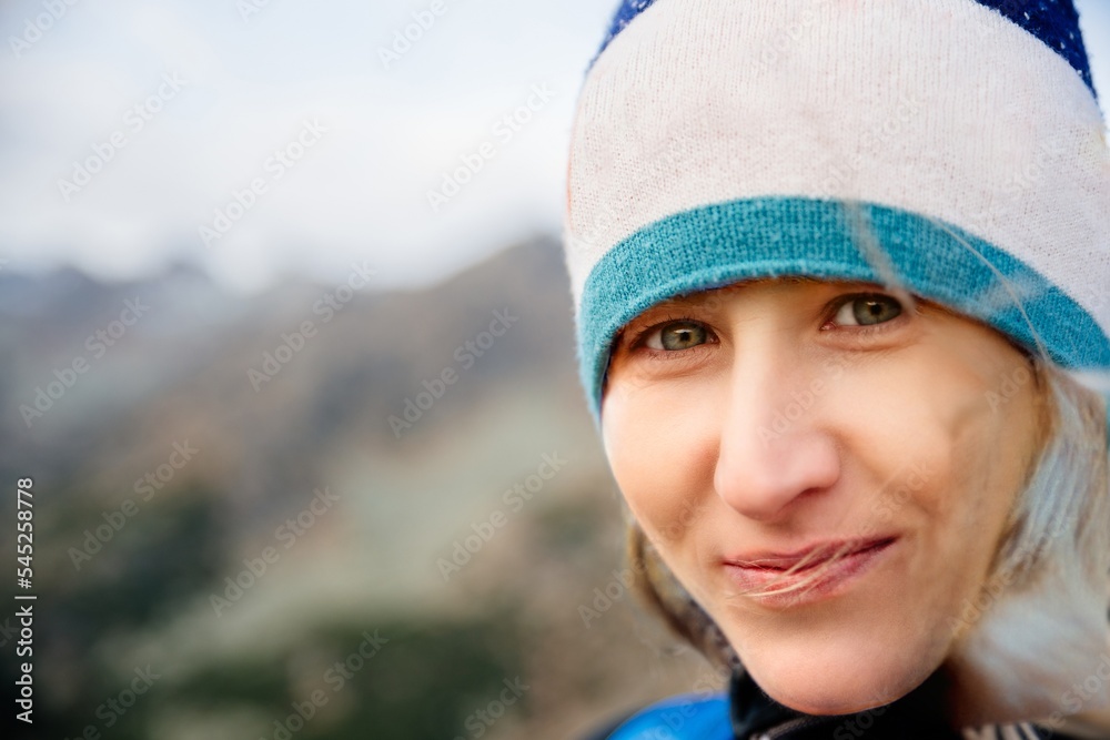 Close up portrait of a beautiful blond woman with green eyes. A woman is wearing a hat a photo taken during an autumn hike in the mountains