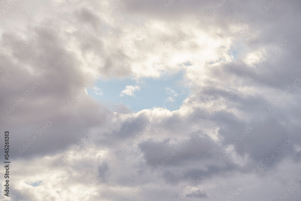 Blue sky gap in the middle of white rain clouds