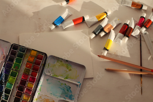 Fototapeta Naklejka Na Ścianę i Meble -  Creative mess in the artistic workshop. Empty copy space canvas, acryli, watercolor paints in tubes, brushes, pencils, pastels, palette knife.