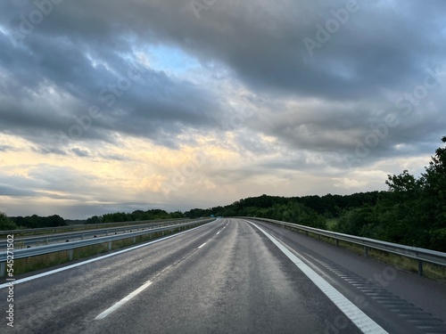 Empty highway in the fields, stormy sky © Oksana