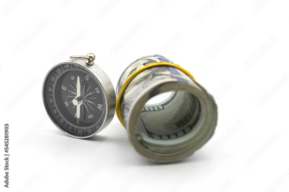 Classic navigation compass and bundle of money roll of dollars isolated on white background Classic navigation compass and bundle of money roll of dollars isolated on white background