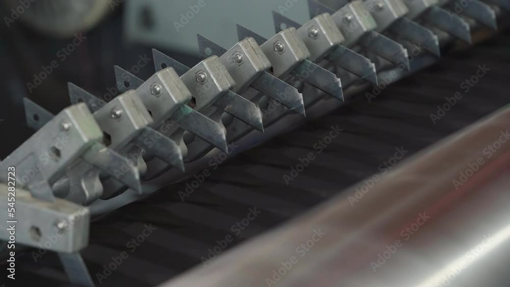 Close-up of production machine mechanism with sharp blades. Blades of the production machinery for cutting the fabric material. Production machine blades processing the sustainable textile. Equipment. Close-up of production machine mechanism with sharp blades. Blades of the production machinery for cutting the fabric material. Production machine blades processing the sustainable textile. Equipment.
