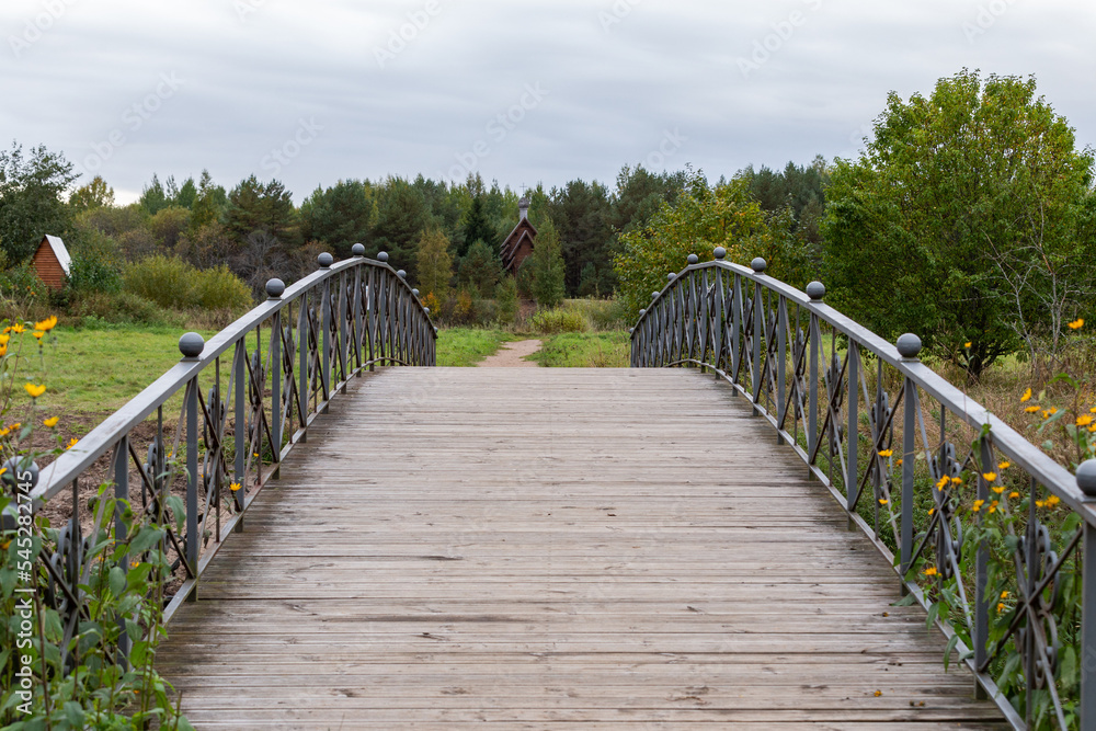 Wooden bridge in the Leningrad region with a railing in autumn weather. Wooden bridge in the Leningrad region with a railing in autumn weather.