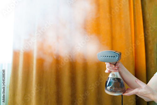 Valokuva Working portable hand steamer for clothes in women's hands.