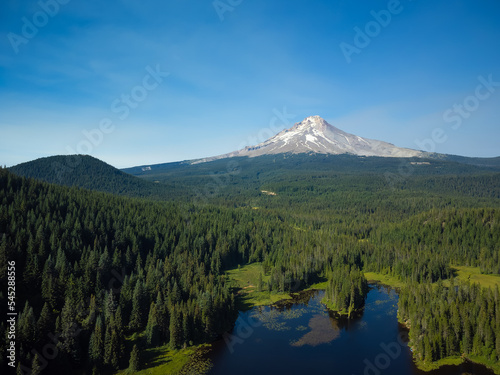 Picturesque landscape, beautiful nature. A high, snow-covered mountain, a dormant volcano. Green, hilly meadow and small lake. Ecology, environmental protection, geology, weather.