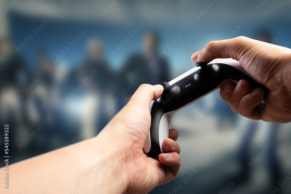Fototapeta premium Entertaining video games. A gamer holds a GAM22ICB joystick in his hands. The background is a video game on the big screen of a personal computer, TV. Virtual reality, cyberspace.