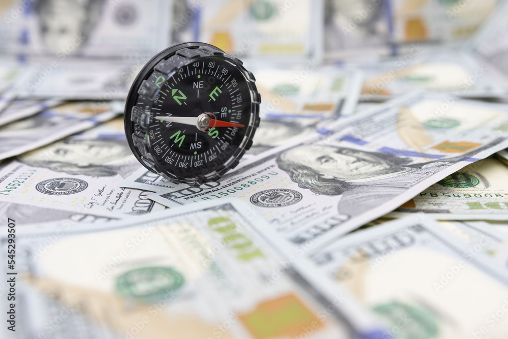 Classic navigational compass on the background of one hundred dollar bills Classic navigational compass on the background of one hundred dollar bills